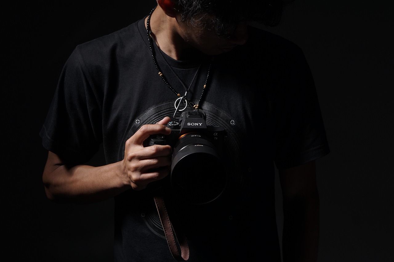 A videographer holding a camera in low light