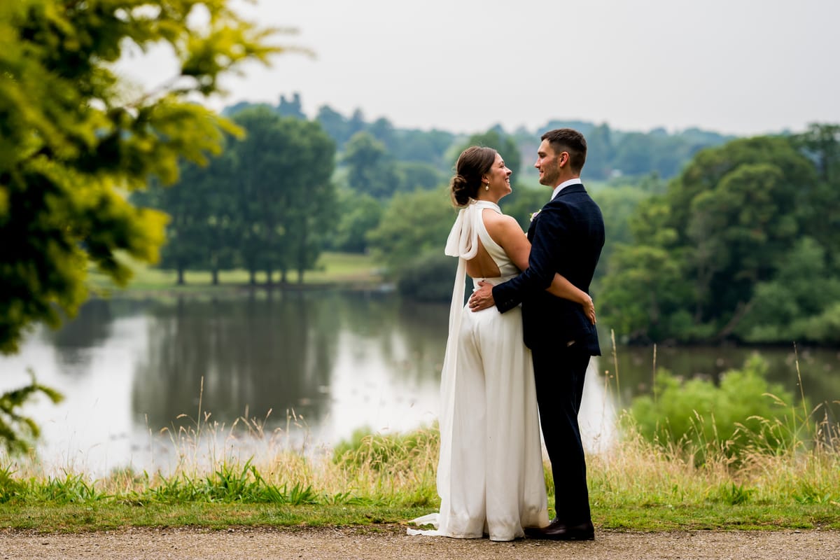 A couple by a lake on their wedding day, the photograph becoming a moving scene